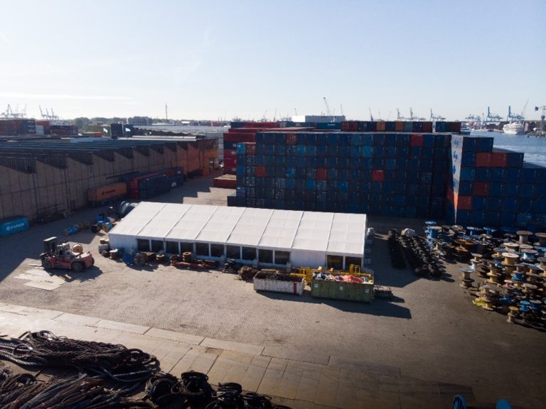 Tijdelijke loods in een haven met containers.